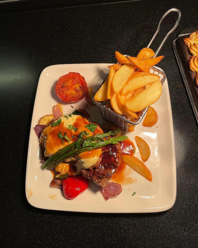 En tallrik med kött och pommes.