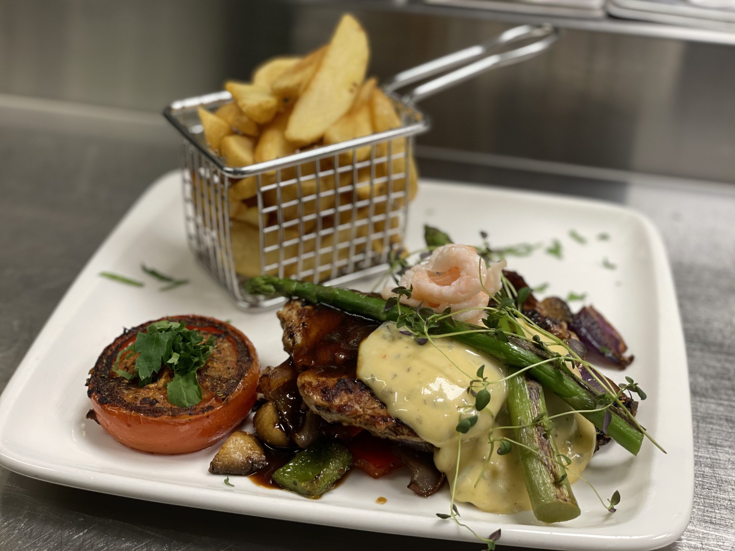 En tallrik serverad med pommes, kött och andra delikatsesser.