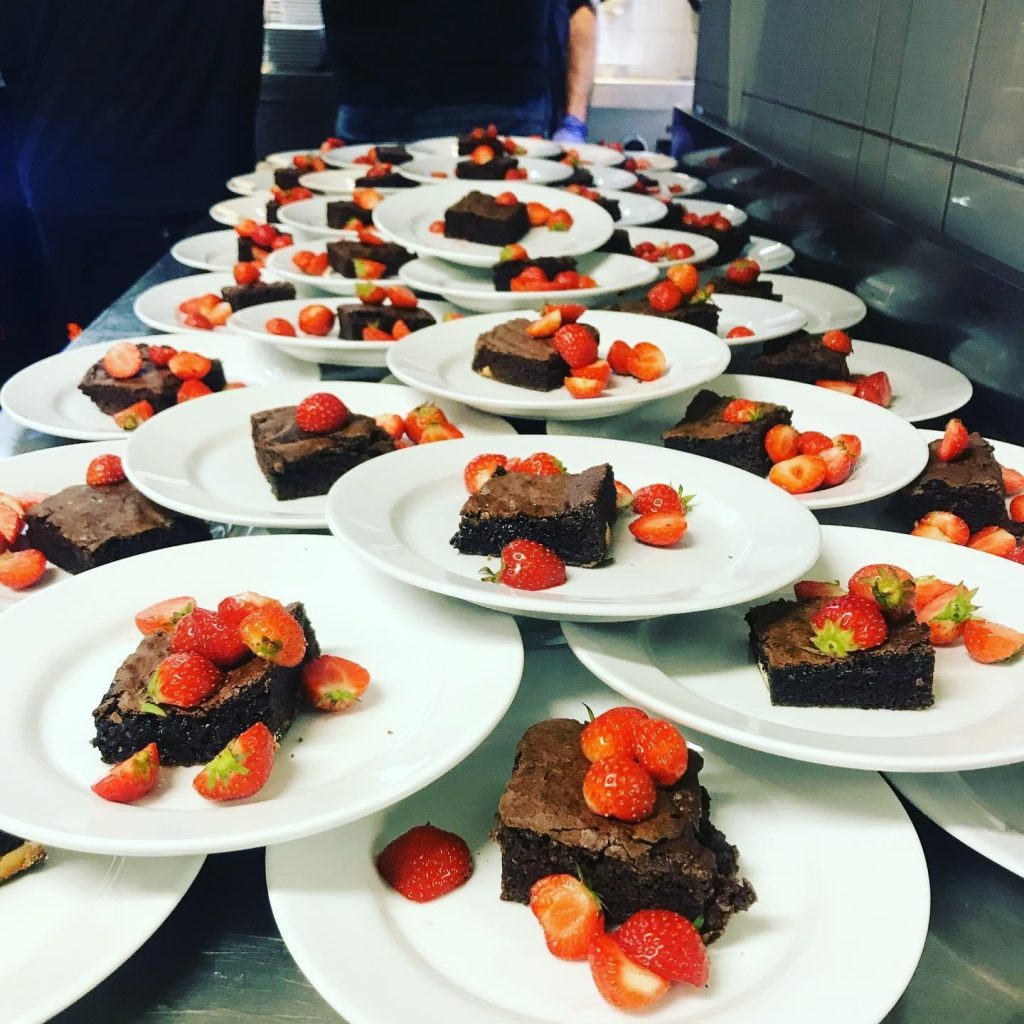 Efterrätter som är kladdkaka med grädde och jordgubbe. 